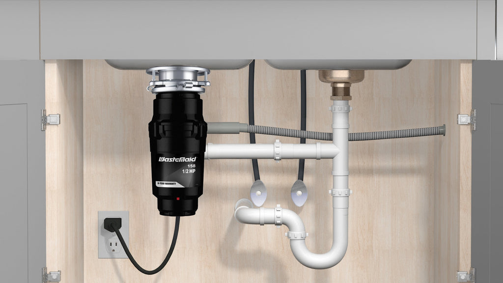 Garbage disposal unit under a kitchen sink with visible plumbing and electrical outlet.