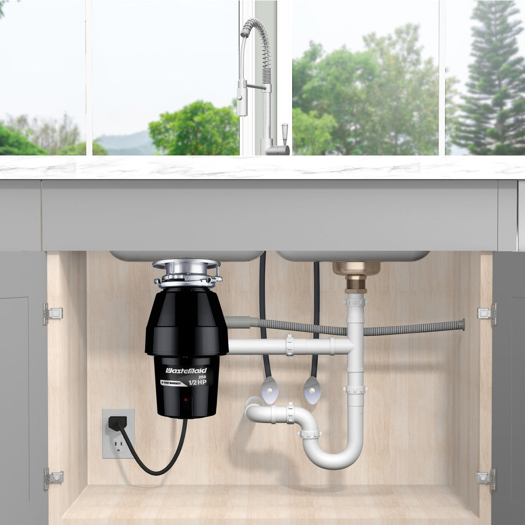 Garbage disposal unit under a kitchen sink with visible plumbing and electrical outlet.