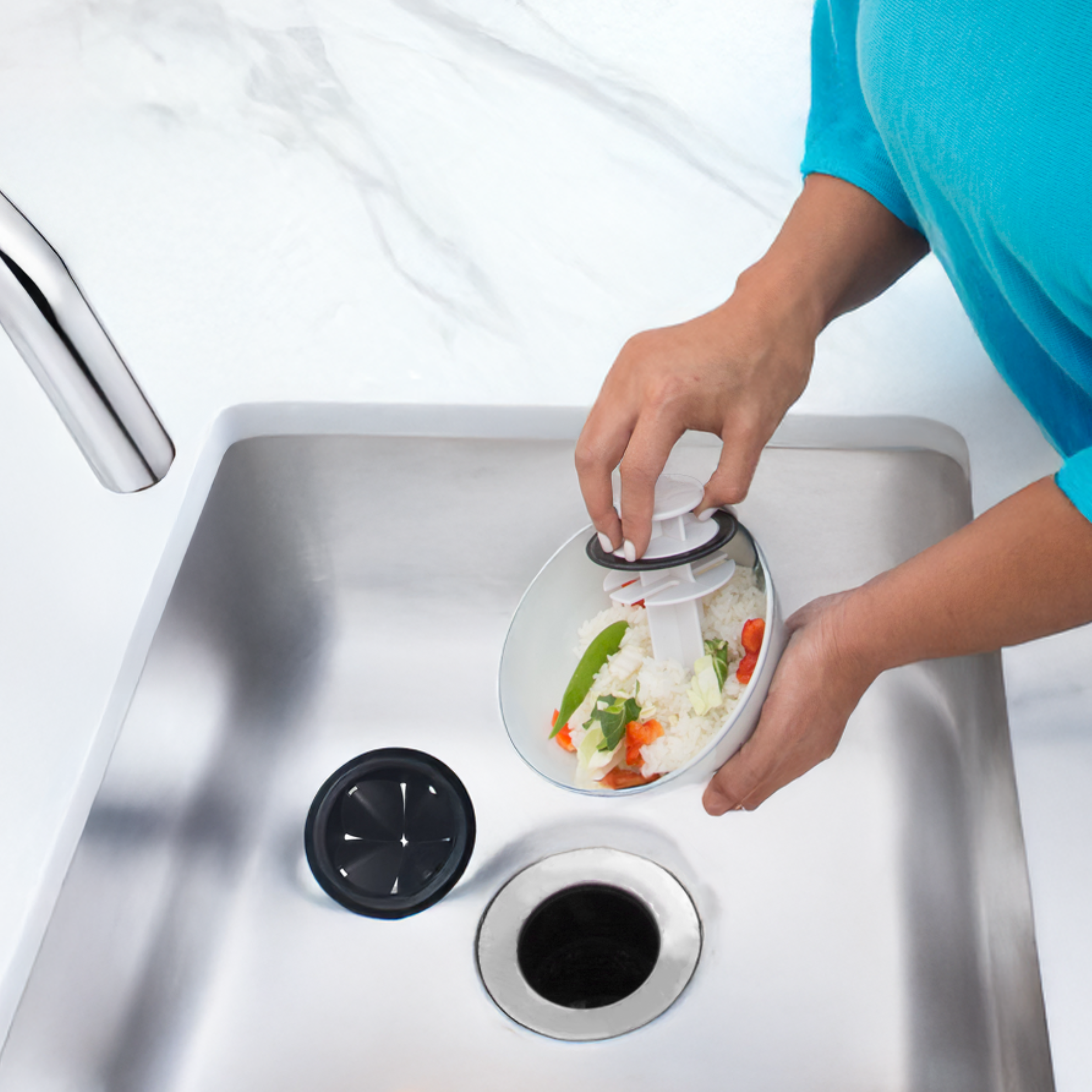 Lady pushing food into sink disposal with tool
