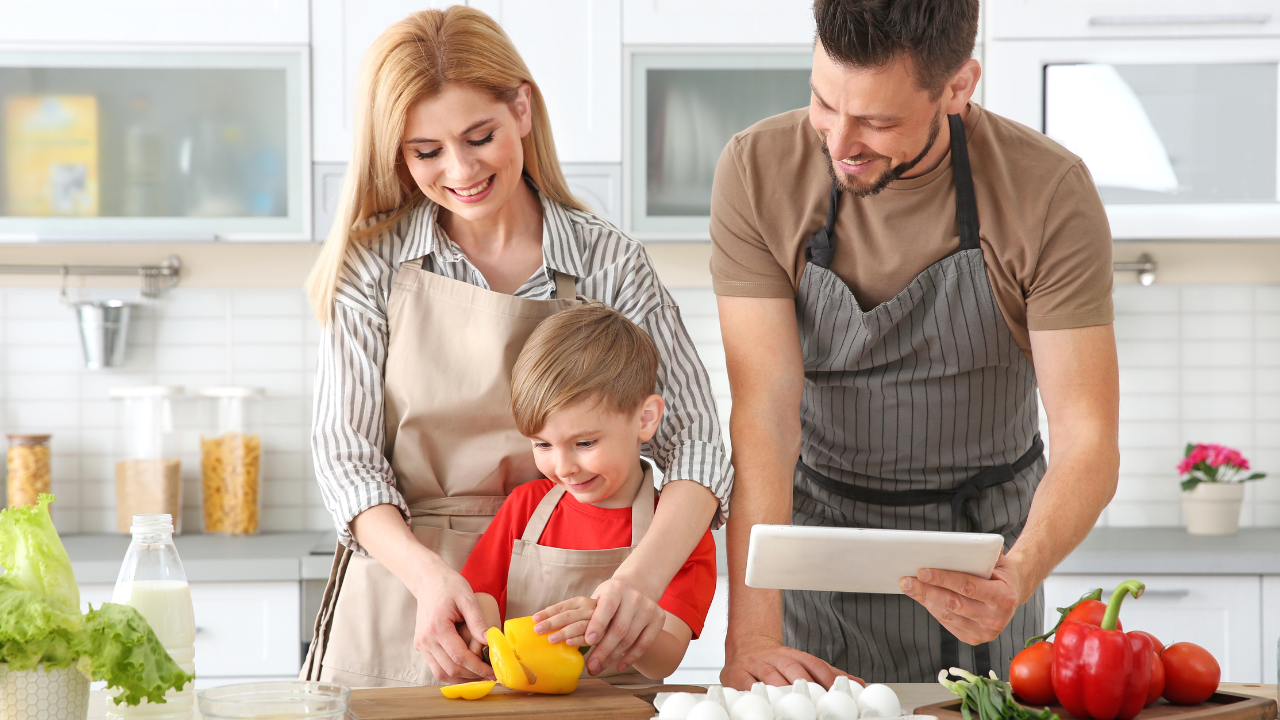 Family in a kitchen preparing food together with a tablet.